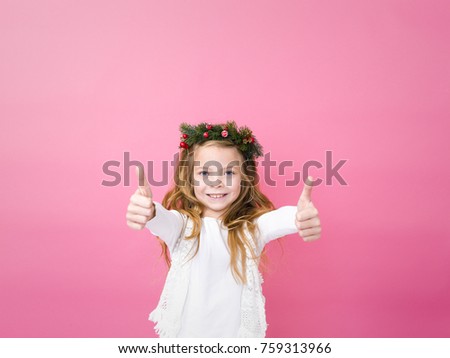 beautiful blond girl with christmas decoration on her head in front of pink background