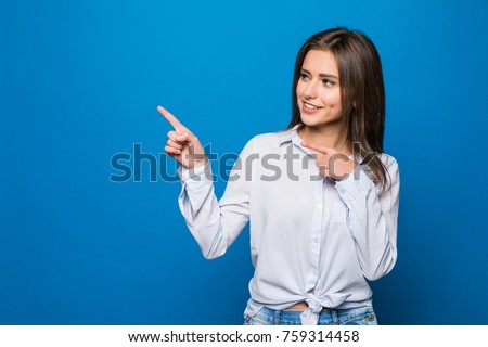 Smiling business woman pointing finger at copy space. White shirt. Long hair. Blue wall. Royalty-Free Stock Photo #759314458