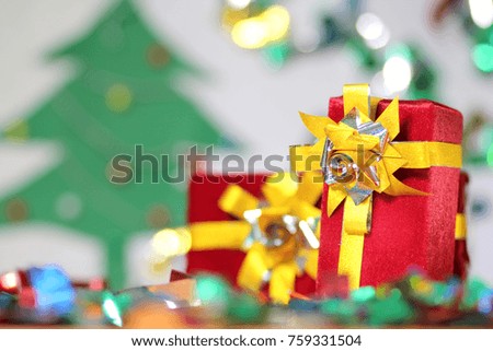 Cristmas gift in red box with blurred christmas tree and bokeh background.