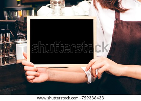 Barista holding chalkboard  in coffee shop restaurant
