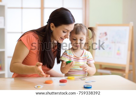 Woman teacher play with preschooler child in day care center. Royalty-Free Stock Photo #759338392