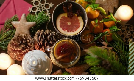 4K Hands Putting a mug of Christmas Tea on Decorated Table with Festive Candles, Mandarins, Gingerbread Cookies, etc