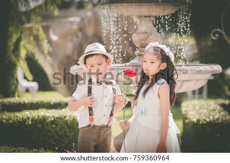 Little girl and boy  enjoy in wedding dress in garden with old classic style stone fountain with flowing water concept for valentine day