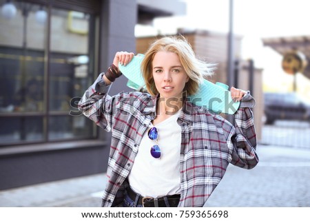Attractive hipster girl with skateboard on street