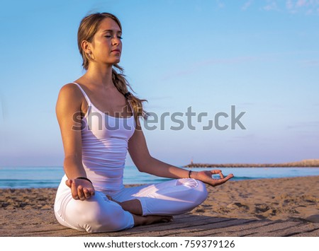 young pretty girl doing sport and yoga on the beach
