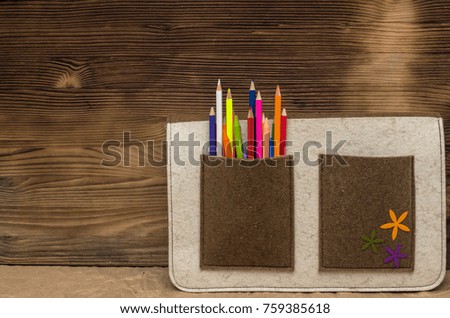 Color pencils in a school bag pocket on wooden wall background with copy space. Drawing set. Artist bag. Back to school.