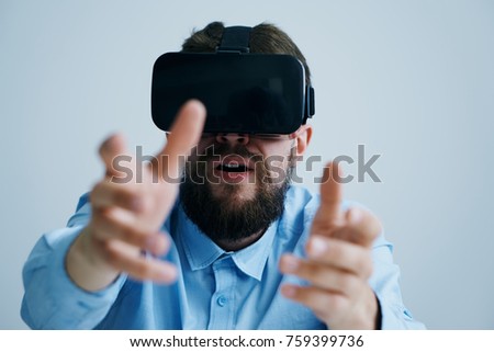 Young guy with a beard on a white isolated background in virtual reality glasses.