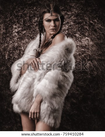 Caucasian female model in fur white fur jacket against brown fur background in native american style makeup
