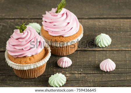 Closeup of cupcakes with vanilla, berries, pink and white cream, chocolate and sprinkles on wooden background. Selective focus. Sweet dessert tasty food concept muffin.