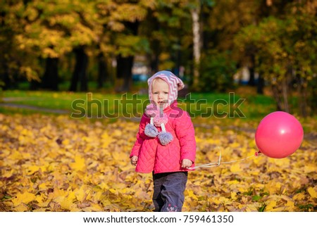 baby girl walking in autumn Park with a bouncy ball