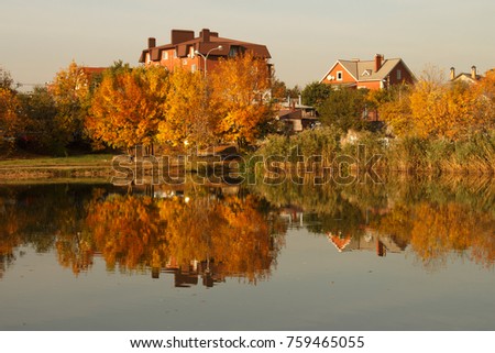 Trees and house reflected in the water. Autumn.