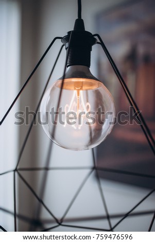 Close up modern tungsten lamp. White wall and with a big picture of New York and Brooklyn Bridge on the background. Orange warm light. Modern interior.