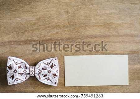 Embroidered Bow Tie and Empty Card on Wooden Brown Background. Father's day Concept. Rustic Style