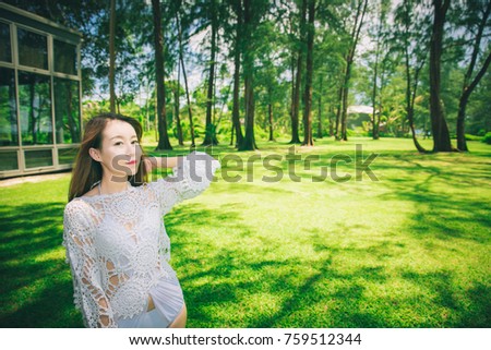 Young female model in white bikini and swimsuit on the background of greens and trees on the beach of Phuket Thailand. Tourism, happiness, trip concept