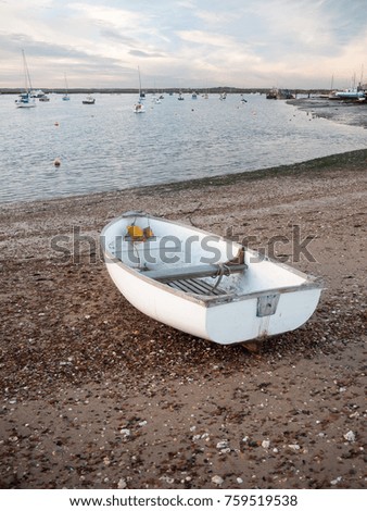 small white private boat parked moored on beach front bay ; west mersea, essex, england, uk