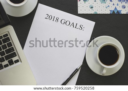 2018 goals paper,pen,white coffee cups with saucers,laptop on a black concrete background, top view