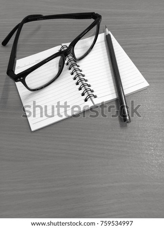 Education book glasses pen on wood table background vintage black and white