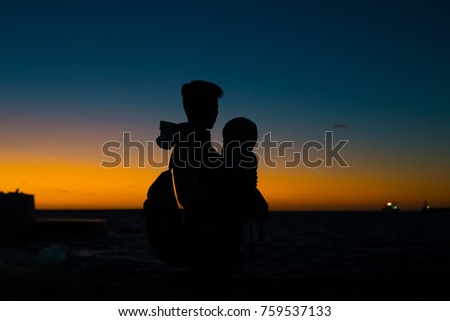 Mother holding her child in her arms at sunset