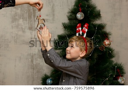 little boy posing with Xmas accessories in front of an Xmas tree