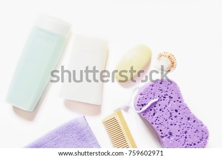 Flat lay spa cosmetics, organic bath products. Light blue shampoo bottle, white shower gel, natural soap, wooden comb, purple sponge and terry towel. Top view stock photo. Cleanliness concept