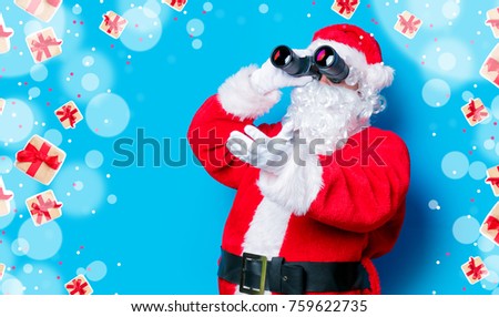 Funny Santa Claus have a fun with binoculars on blue background