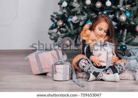 child holds a new year's gift, against tree, smiling