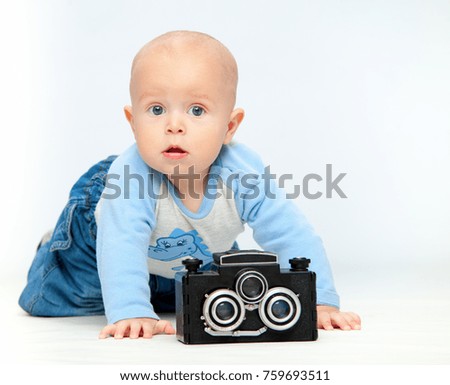 A small child and a camera on a neutral white background.