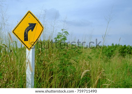 Right bend traffic warning sign on feather grass field against blue sky background