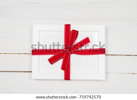 Gift wrapped blank frame over a wooden background