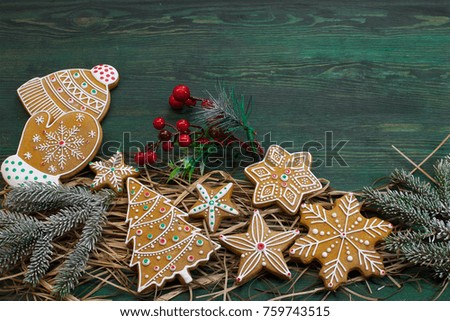 On a green wooden background lies a group of different gingerbread and small jewelry. Color photo.