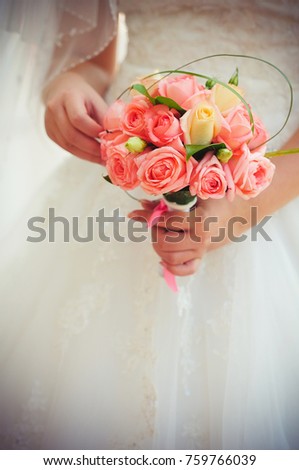 pink wedding bouquet from roses in hands of the bride in a white dress, gentle warm toning.