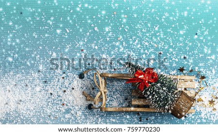 Christmas tree with bow on wooden sleigh on a blue background