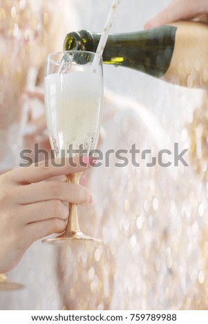 Hand pouring glasses with christmas champagne during the party