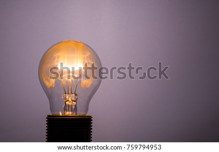 Horizontal photo with single glass bulb. The bulb is switched on but the wire is burning. The smoke colored to orange by fire filling inner space.  The bulb is in socket.
