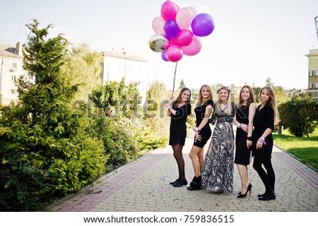 Five girls wear on black with balloons at hen party. 
