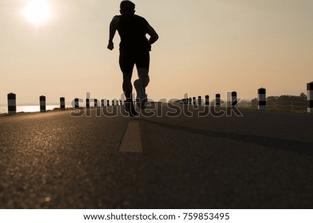 Asia young man running in the time during sunrise on dam road exercise.Healthy lifestyle