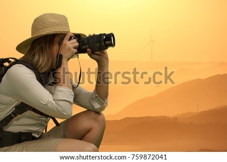 Pretty Lady in Safari Dress crouching down and taking Photographs at Sunset
