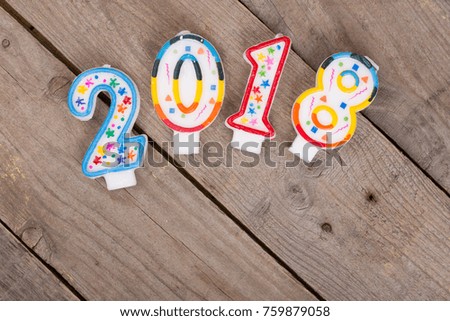 New year concept - inscription 2018 make of candles on brown wooden background