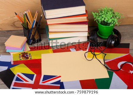 Learning languages concept - blank paper, flags, books, headphones, pencils on wooden background Royalty-Free Stock Photo #759879196
