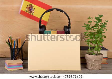 Concept of learning the spanish language - blank paper, flag of the Spain, books, headphones, pencils on wooden background