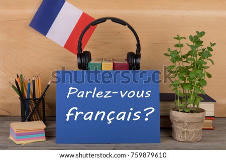 concept of learning French language - paper with text "Parlez-vous français?" (Parlez vous francais?), flag of the France, books, headphones, pencils on wooden background Royalty-Free Stock Photo #759879610