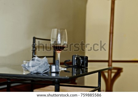 a glass of wine, a camera and a napkin on a glass table
