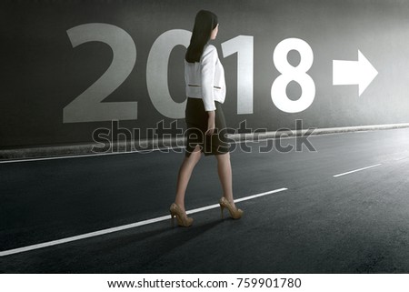 Beautiful asian business woman walking out from tunnel with 2018 on the wall