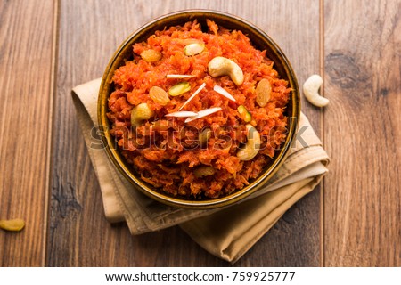 Gajar ka halwa is a carrot-based sweet dessert pudding from India. Garnished with Cashew/almond nuts and Served in a bowl over colourful/wood background Royalty-Free Stock Photo #759925777