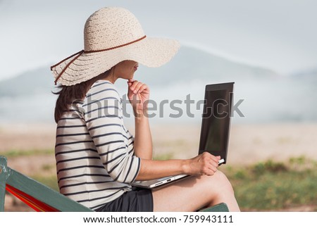 Beautiful women are using a laptop to buy or sell with online shopping from e-commerce. Relax and enjoy on the beach.