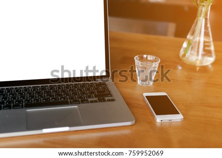 Laptop computer with blank white screen on table in coffee shop, Conceptual workspace.