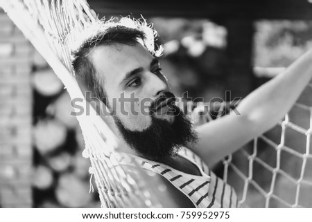bearded man smiling, resting, lying hammock on a warm summer day. sunset sun, rest in a hammock after a hard day.