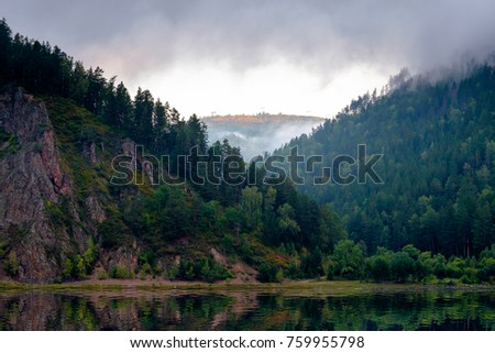 Very beautiful picture with the mountains in the background, over the pond the mist and the rising sun