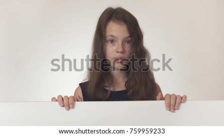 Beautiful girl teenager holding a poster with information and is surprised on a white background