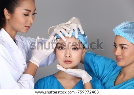 Group of Asian Doctor Nurse check face forehead  structure before plastic surgery and inject beauty chemical syringe to patient, Studio lighting grey background, concept many hands